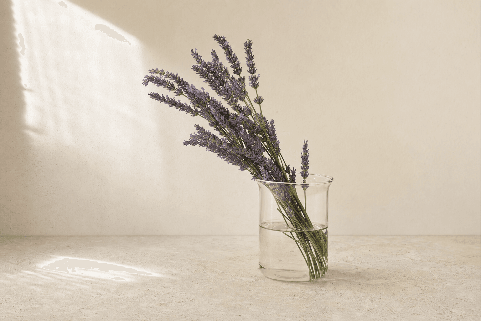A small amber jar with dried lavender sprigs on a pale linen surface.